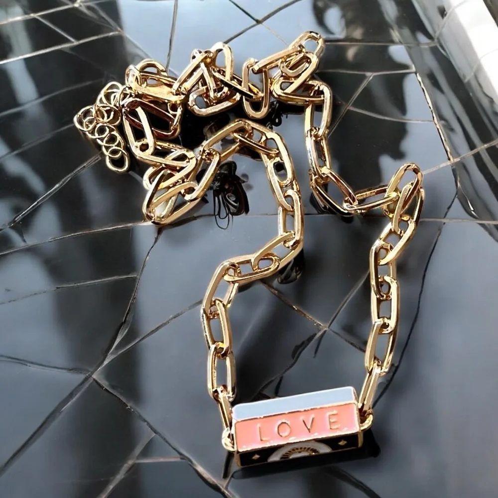 Gold toned chains with black, white, gold, and pastel pink enamel charms.